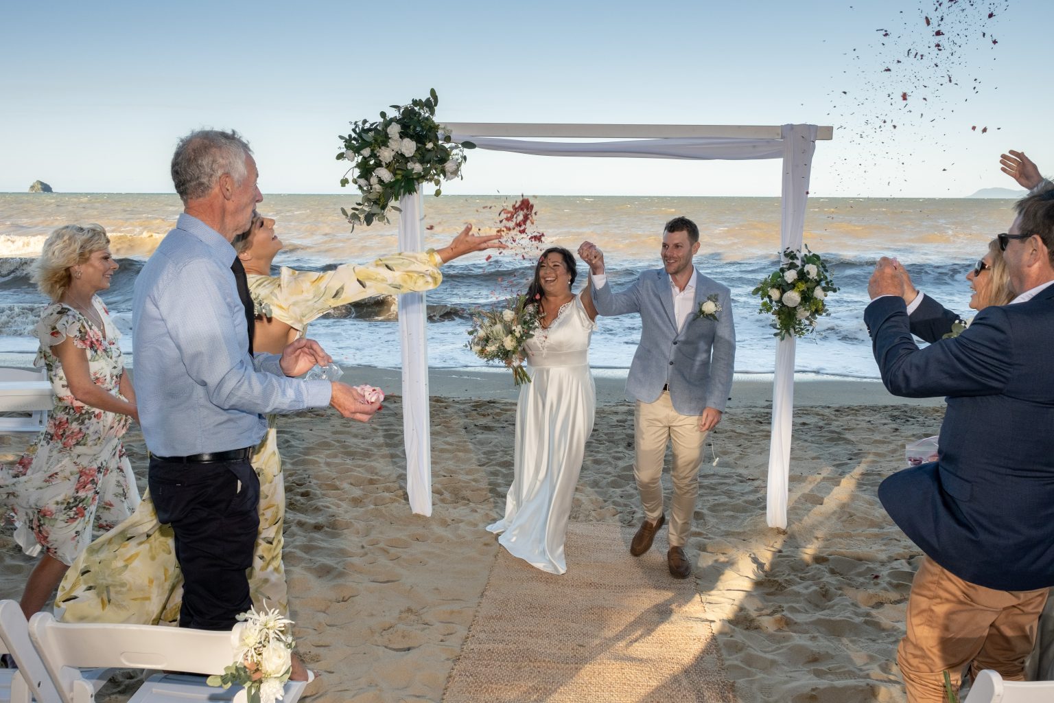 Melaleuca Resort - Palm cove weddings - bride and groom right in front of beach and people throwing flower pedals