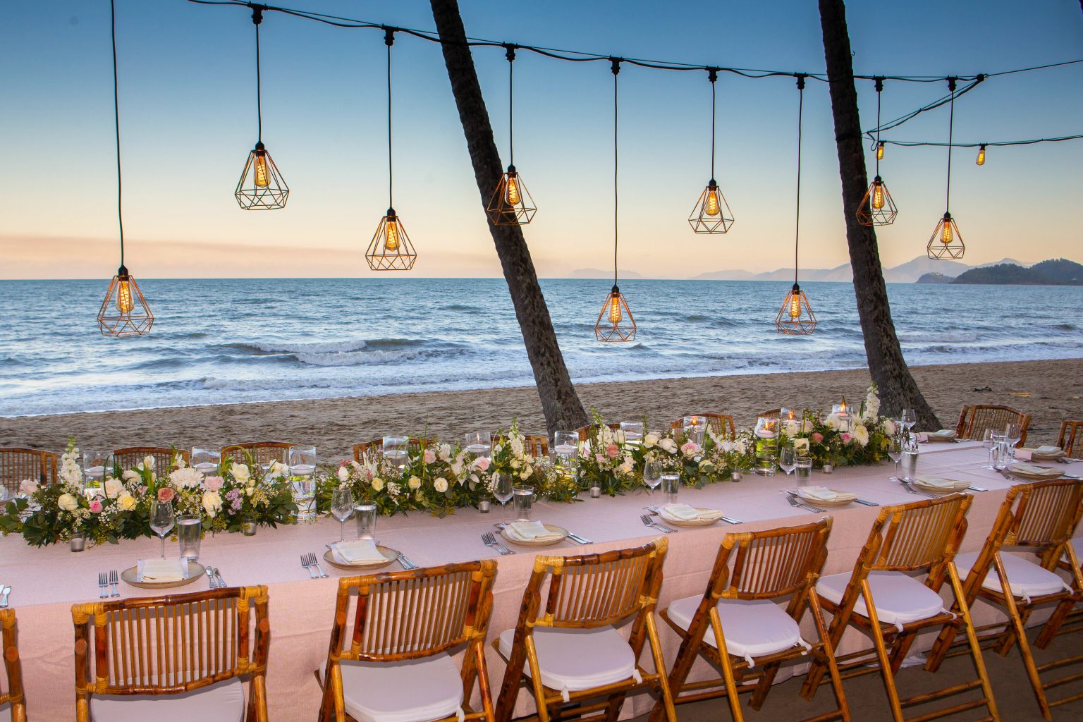 Melaleuca Resort - Palm cove weddings - Bridal table setup on the beach with beautiful flowers and cane chairs