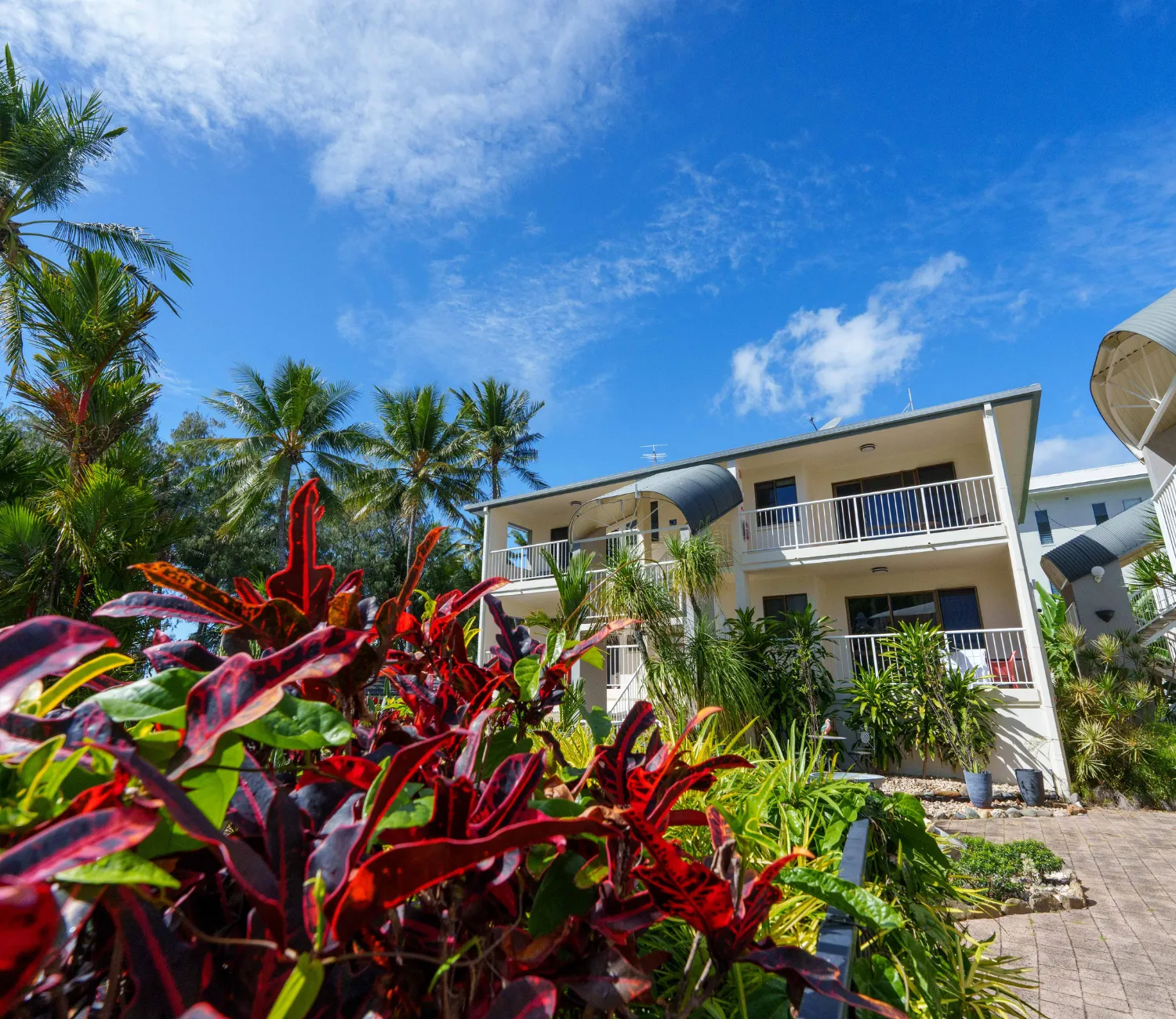 view of one of the apartment blocks at Melaleuca resort from below behind a garden