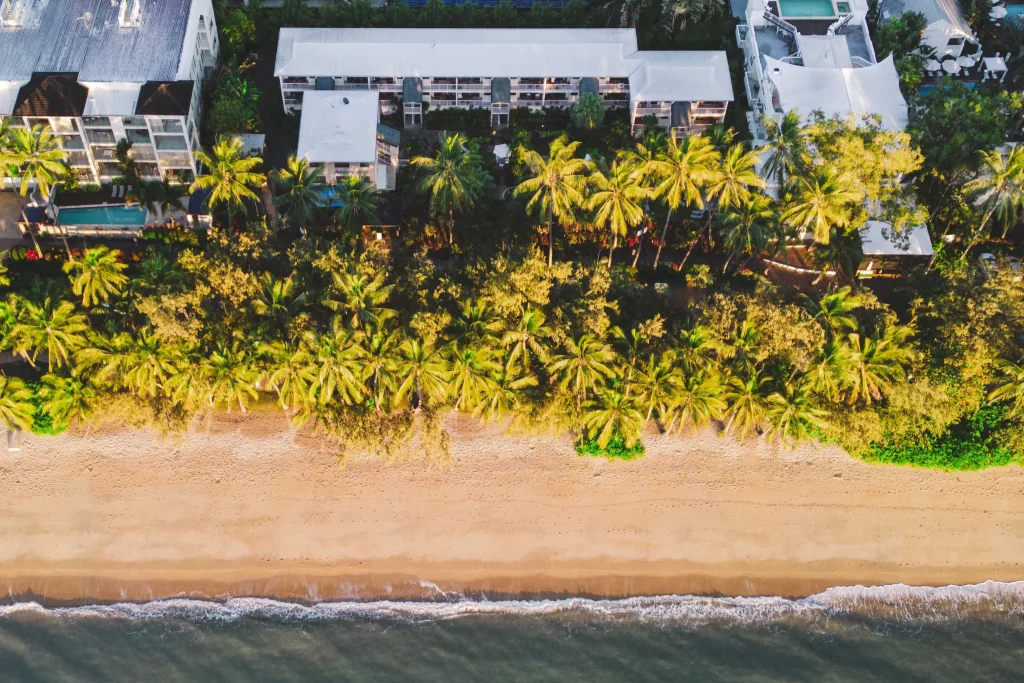 birds eye view of the Melaleuca Resort property and layout with a line of palms trees separating it from the beach.